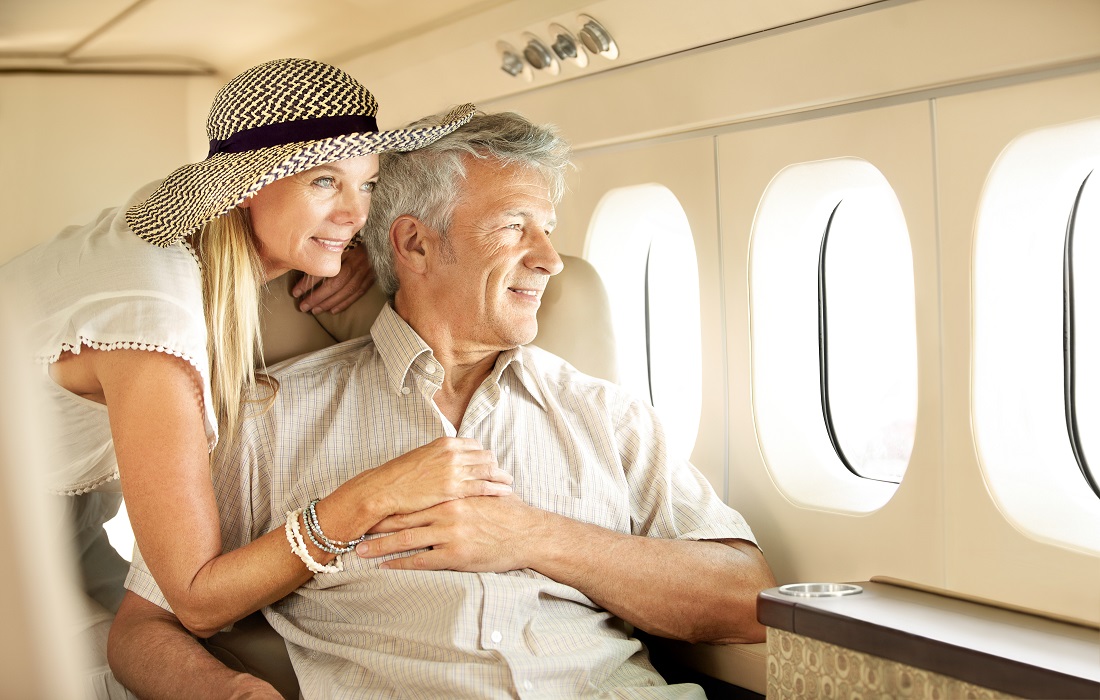 Taking-a-luxury-trip-smiling-senior-couple-on-an-airplane-looking-out-the-window